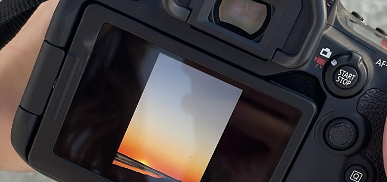 Photographer holding a Canon camera on a beach